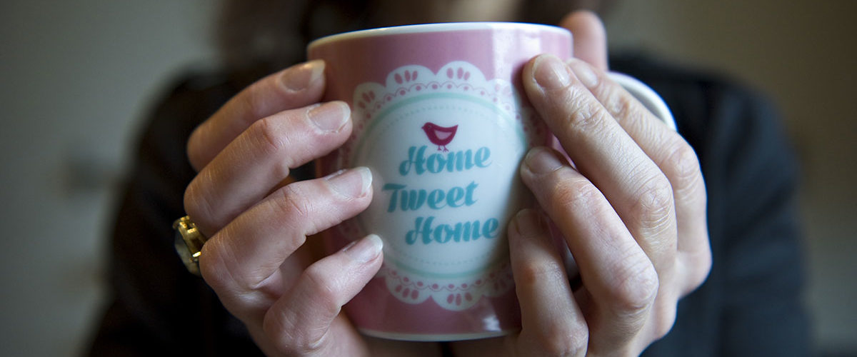Woman holding mug that reads 'Home Tweet Home'